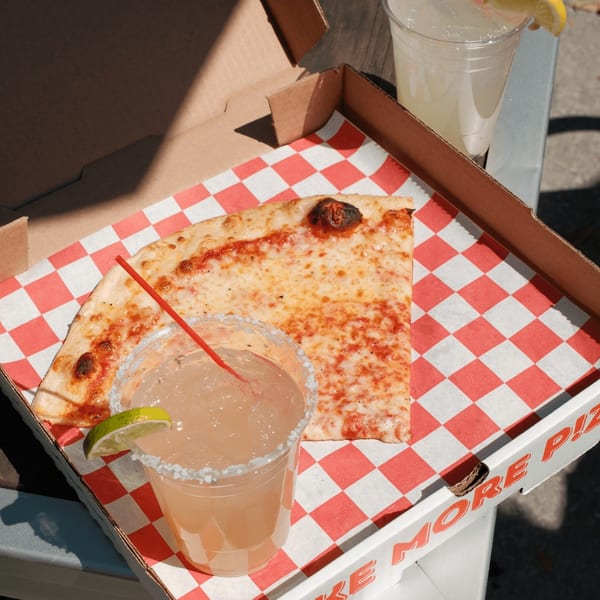 A slice of Pizza by the Sea cheese pizza and a margarita in a pizza box.