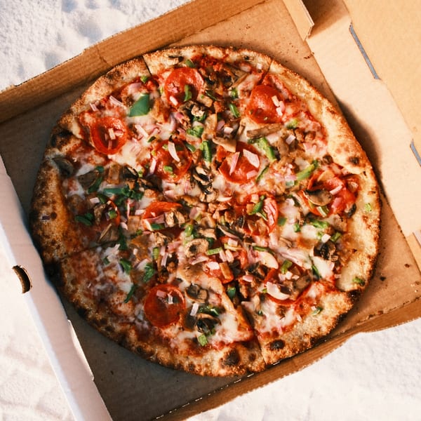 A Pizza by the Sea pizza with pepperoni, mushrooms, and green peppers in a cardboard box.